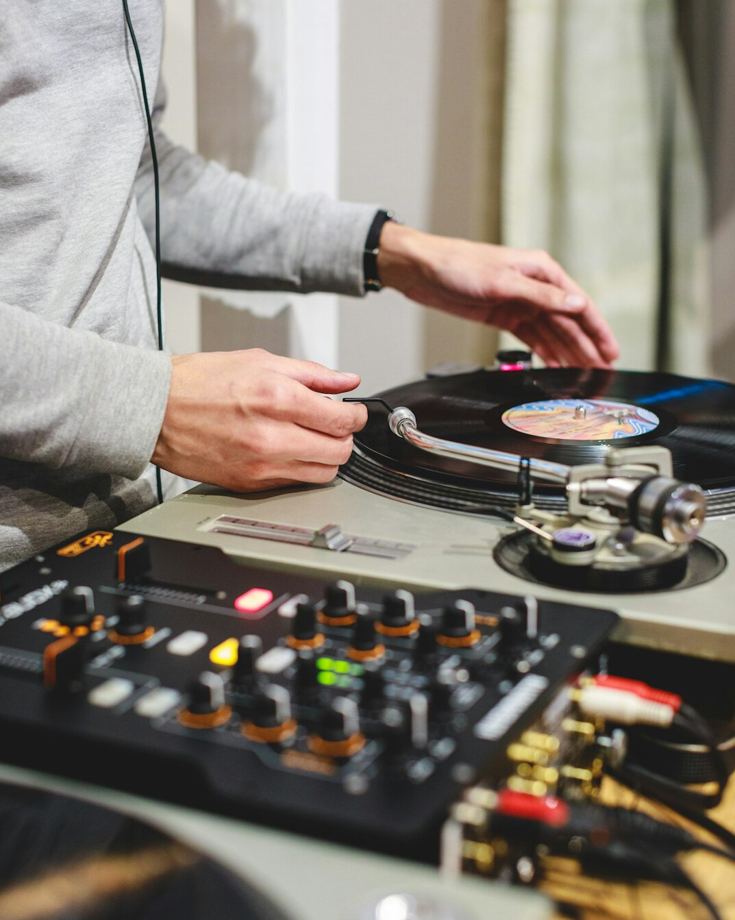 Hands adjusting a mixing console with headphones nearby