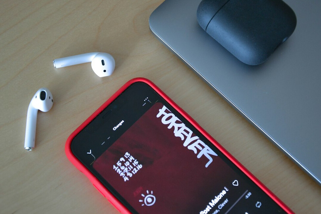 Smartphone showing a podcast app with headphones on a desk